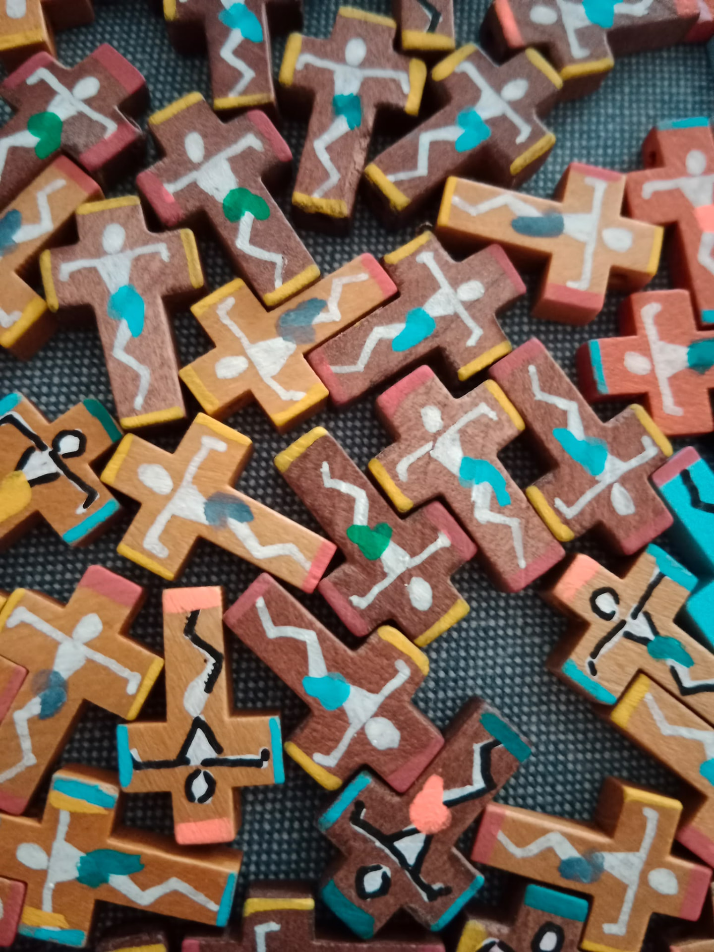 Fotografía de pequeñas cruces de madera pintadas a mano con figuras de Jesús y detalles de colores